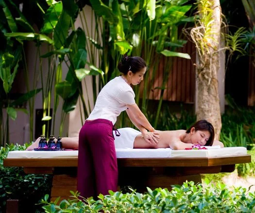 woman receiving lomilomi massage in an outdoor garden setting